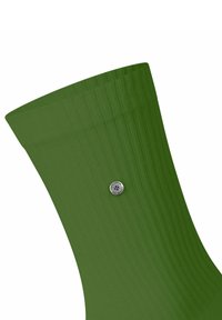Grüne gerippte Socke mit glatter Textur, mit einem silbernen runden Logo-Detail nahe der Oberkante. Die Socke verläuft nach oben zur Öffnung.