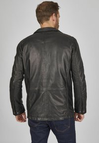 Schwarze Lederjacke mit glatter Textur, klassischem Design, Eingrifftaschenkragen und Knopfdetails. Ansicht von hinten, die die Nähte zeigt.