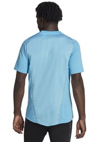 Lichtblauw sportshirt met korte mouwen, met kleurrijke stiksels langs de naden en een gestructureerde stof.