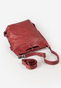 Rode leren tas met een zachte textuur, rechthoekige vorm, verstelbare schouderband en drukknoopsluiting. Inclusief een afneembare band voor veelzijdig dragen.