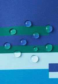 Teksturowana tkanina o niebieskich i zielonych paskach z kroplami wody na powierzchni, prezentująca połączenie żywych kolorów i materiałów.
