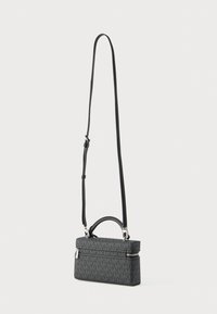 Strakke zwarte handtas met een gestructureerd rechthoekig ontwerp, voorzien van een geprint buitenkant, ritssluiting en verstelbare riem.