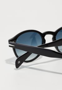 Round sunglasses with black frames, blue gradient lenses, and sleek black arms. Notable logo detail on temple.