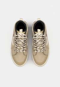 Beige mid-top lenkkarit, joissa on teksturoitu pinta, kontrastivalkoiset yksityiskohdat ja moniväriset nauhat. Liukas pohja ja pyöreä kärki.