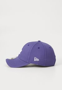 Boné de basebol roxo com aba curva, apresentado com detalhes de logótipos bordados brancos e ilhós. Material em algodão com acabamento texturizado.