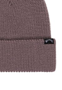 Berretto lavorato a maglia in un colore mauve tenue, con risvolto e una piccola etichetta nera con testo bianco sul lato. Texture morbida con trama fitta.