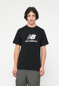 Juodas medvilnės marškinėliai su ryškiu baltu "New Balance" logotipu. Klasikinis apvalios kaklo dizainas su trumpomis rankovėmis. Paprasta, vienspalvė.