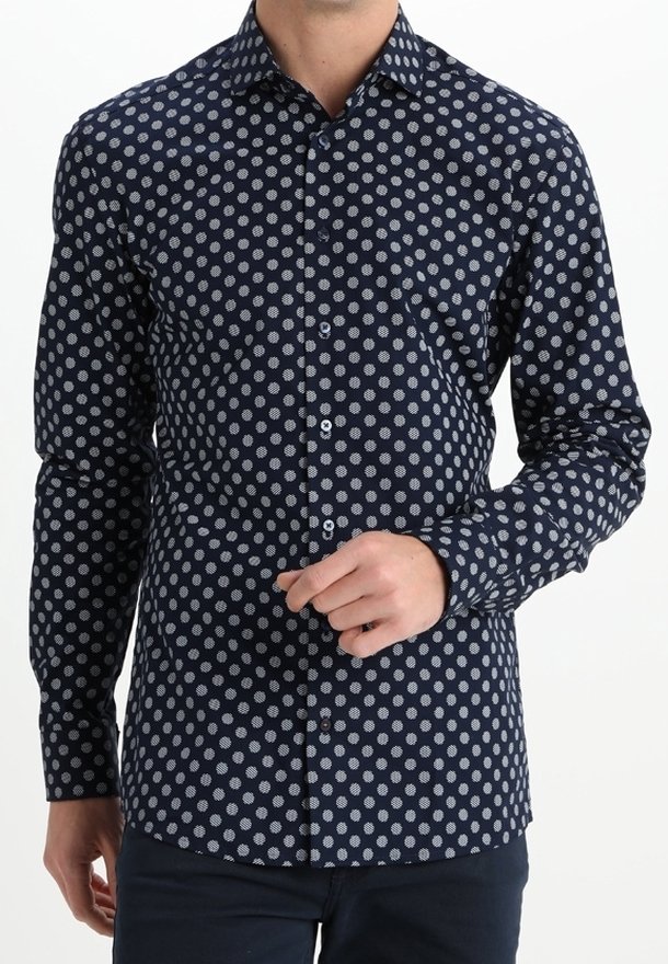 Marineblauw overhemd met knopen en een patroon van witte stippen, lange mouwen en een klassieke kraag met een zachte katoenen textuur.