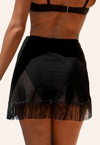 Copricostume nero da spiaggia con tessuto trasparente e orlo frangiato, dotato di vita aderente e superficie liscia. Design semplice ed elegante.