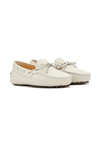 Los zapatos mocasines de cuero beige presentan una puntera redondeada, detalles de costura y cordones en la parte delantera. Suela texturizada con pequeños grips de goma.