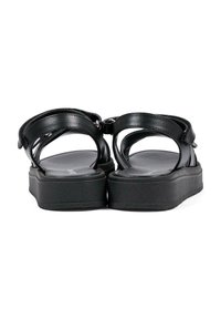 Czarne płaskie sandały z grubymi podeszwami, otwartymi piętami i paskami przy kostce zamykanymi na rzep, widoczne od tyłu na białym tle.