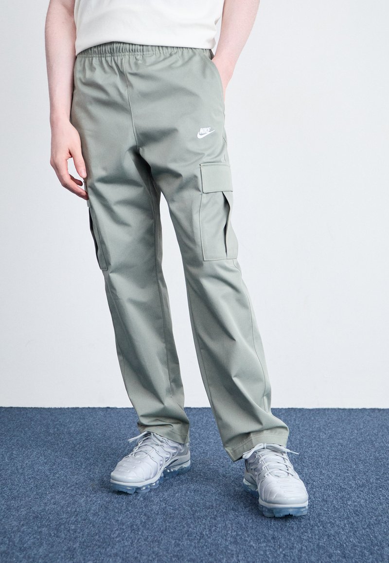 Νάιike cargo παντελόνι σε ανοιχτό πράσινο ύφασμα, με ελαστική μέση και πλαινές τσέπες. Συνδυασμένο με γκρι αθλητικά παπούτσια.