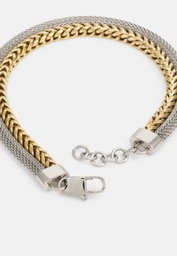 Bracciale in metallo dorato e argentato con un mix di maglie lisce e strutturate, dotato di una chiusura sicura e di un'estensione della catena regolabile.