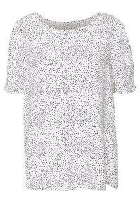 Blusa blanca de manga corta con escote redondo, que presenta un patrón de pequeños puntos negros irregulares distribuidos uniformemente por la tela.