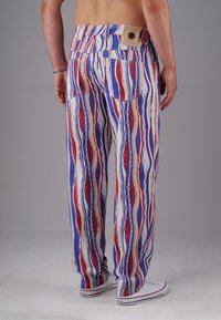 Mehrfarbige Hose mit vertikalen Streifen in Rot, Blau und Gelb. Hergestellt aus leichtem Stoff, mit Gesäßtaschen und einem Etikett am Bund.