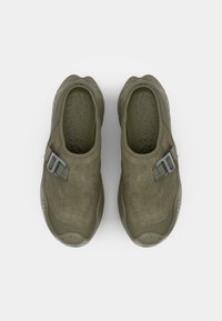 Ελιάς πράσινα slip-on παπούτσια με λείο σουέντ πάνω μέρος, καουτσούκ σόλα και ελαφριά γκρι ρυθμιζόμενη ταινία για καλύτερη εφαρμογή. Ορατή υφή εσωτερικής σόλας.