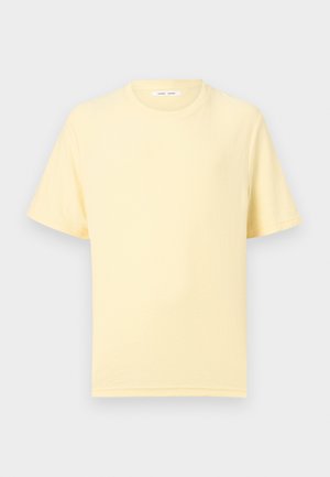 Απαλό κίτρινο κοντομάνικο μπλουζάκι με στρογγυλή λαιμόκοψη και άνετη εφαρμογή σε απλό ανοιχτό φόντο.