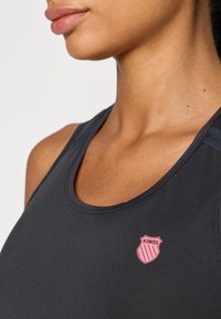 Svart atletisk tanktopp med myk, glatt stoff, rund halslinning og liten rosa K-Swiss-logo på forsiden.