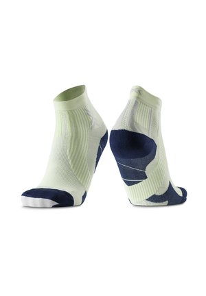 Een paar lichtgroene, laaggesneden sportsokken met marineblauwe hiel-, teen- en boogondersteuningspatronen op een witte achtergrond.