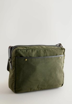 Zöld vászontáska cipzárral, bőr díszítéssel, elülső zsebbel és arany színű szegecsekkel. Téglalap alakú és puha tapintású.