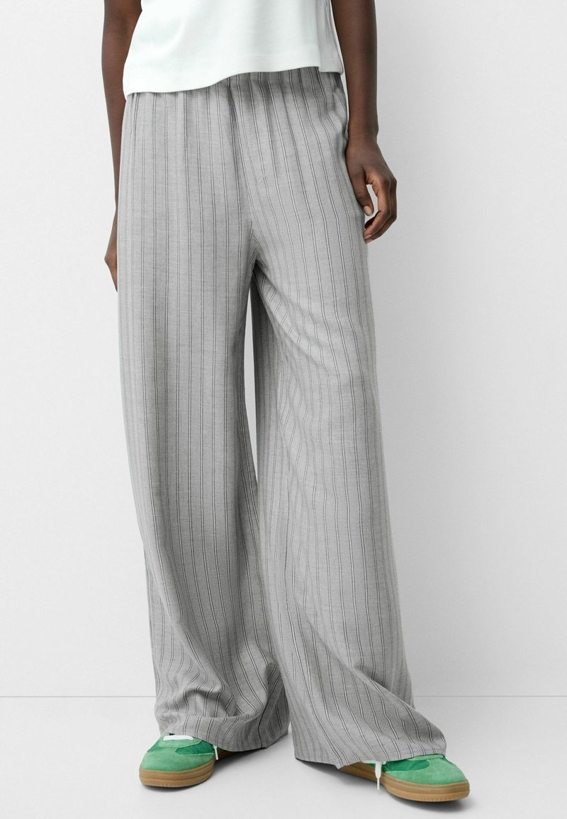 Bredbenta grå byxor med vertikala ränder, gjorda av ett lättviktigt material, med elastisk midja och avslappnad passform.