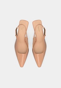 Béžové lakované slingback boty s špičatými prsty, s hladkým svrškem, otevřenými stranami a zlatým dekorativním sponou.