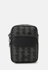 Black geometric pattern bag featuring a smooth, textured finish, top zipper, and a front pocket with embossed branding. Compact rectangular shape.