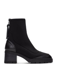 Botas negras hasta el tobillo con un tacón de cuero texturizado, parte superior de tejido suave y suela de goma estriada. Cuenta con un zipper lateral y un detalle de borlas.