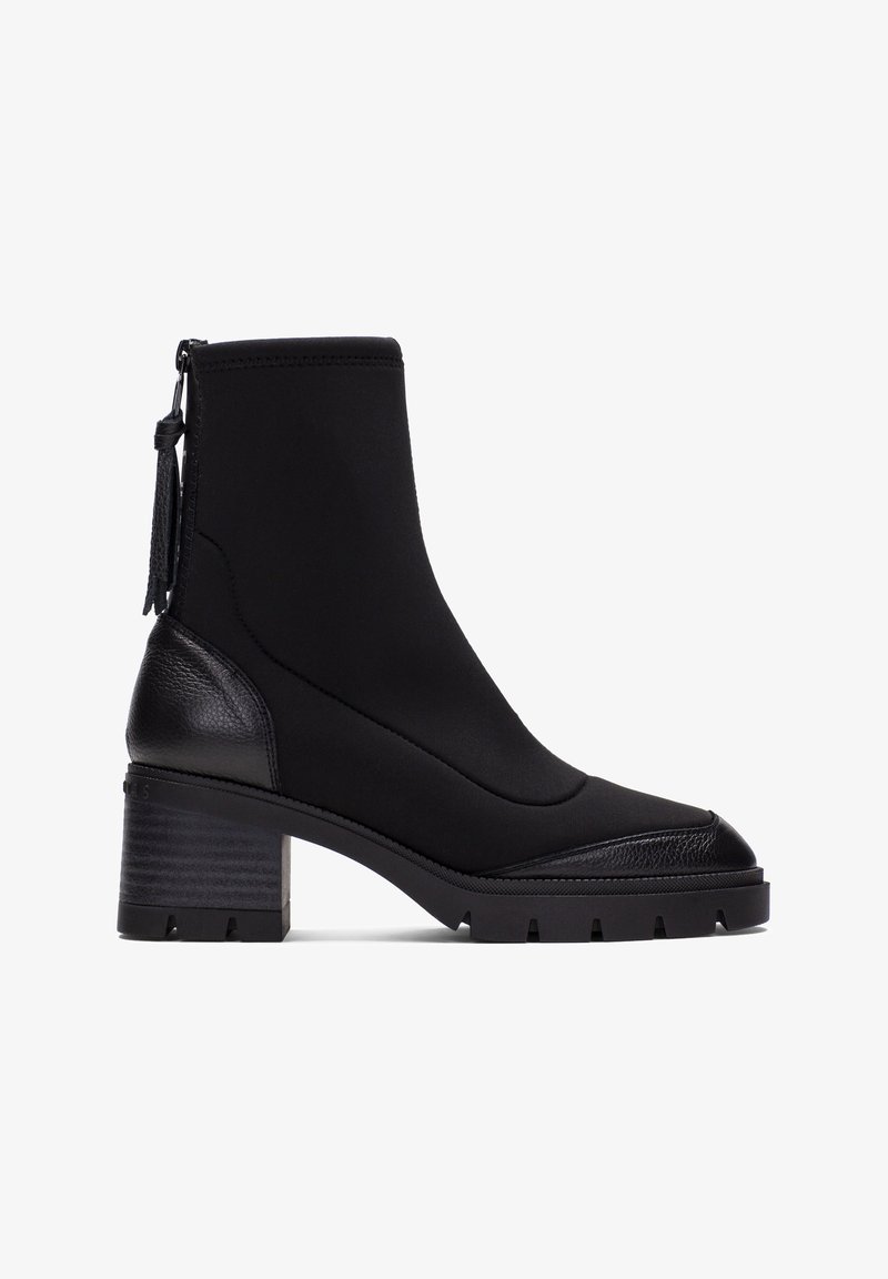 Bottines noires avec un talon en cuir texturé, un dessus en tissu lisse et une semelle en caoutchouc nervurée. Dotées d'une fermeture éclair sur le côté et d'un détail en gland.