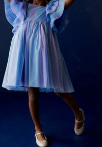 Vaaleansininen ja laventelinvärinen mekko, jossa kimalteleva tyllehelma ja liehuvat hihat. Hopeiset balettitossut täydentävät asun.