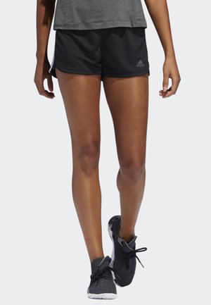 Pantalones cortos deportivos negros hechos de un material ligero, con un ajuste relajado. Combinados con zapatillas gris con cordones.