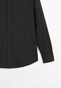 Chemise grise foncée à manches longues avec devant boutonné et un poignet simple, présentée sur un fond blanc.