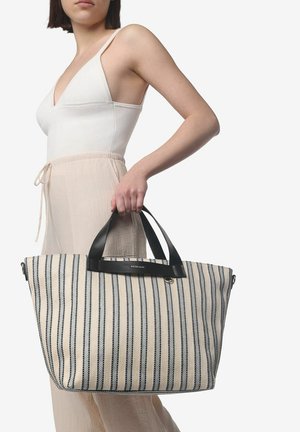 Gestreepte tote bag in crème met zwarte lijnen, met zwarte leren handvaten en logo-detail. Ruim en gestructureerd ontwerp.