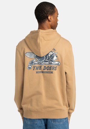 Felpa beige con un design grafico sulla schiena, con il testo "I FATTIVI" e un animale dei cartoni animati che tiene un attrezzo. Tessuto morbido, vestibilità rilassata.