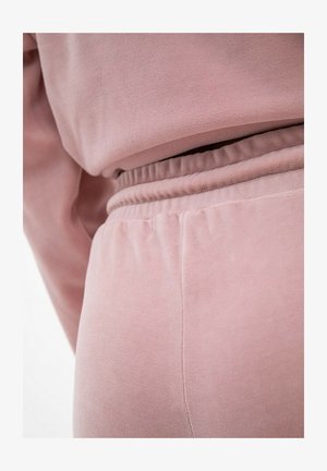 Różowy zestaw odzieży dresowej z weluru o miękkiej teksturze. Pasek w talii jest elastyczny, a szwy starannie przeszyte, co nadaje schludny wygląd.