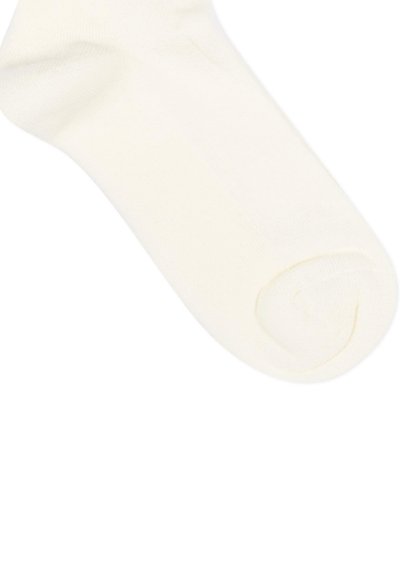Chaussette blanche à la cheville retroussée au niveau de l'orteil, montrant une texture de tissu lisse sur un fond blanc uni.