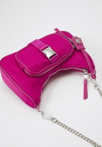 Borsa in nylon fucsia con hardware argentato, dotata di una tasca frontale e tracolla a catena. Texture liscia con una forma strutturata e curva.