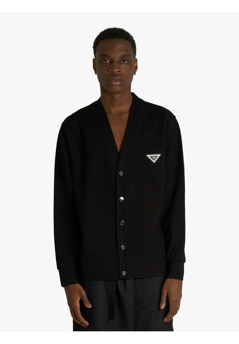 Cardigan nero realizzato con tessuto morbido, dotato di scollo a V, bottoni automatici e una patch con logo triangolare sul petto sinistro. Maniche lunghe.