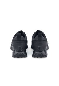 Scarpe sportive nere con suola in gomma testurizzata, tallone rinforzato e tomaia in tessuto. Presentano una linguetta sul retro per un facile indossamento.