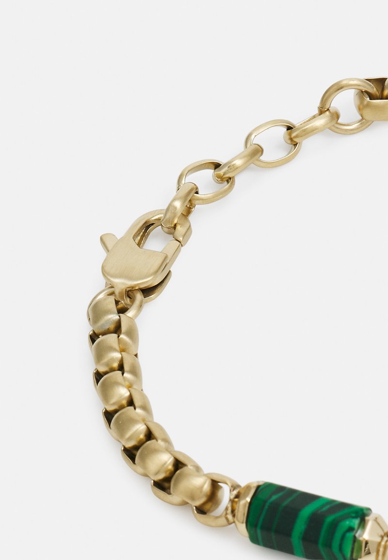 Collier en chaîne dorée avec une perle de malachite, présentant des maillons entrelacés et un fermoir à homard. Texture de surface lisse.