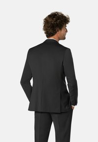 Chaqueta de traje gris carbónico hecha de tela suave, con una sola abertura y solapas de pico, con una textura sutil y dos bolsillos traseros.