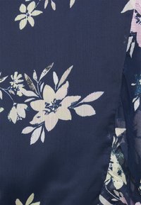 Tecido azul-marinho com um padrão floral apresentando grandes flores amarelo-claro e brancas, acompanhadas por folhas verdes. Textura suave, ligeiramente refletiva.