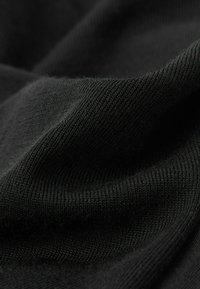 Schwarzer, gestrickter Stoff mit feiner Textur, der dezente Wellen und ein gleichmäßiges Muster zeigt. Weiches, glattes Erscheinungsbild.