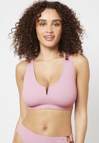 Top court en maille rose avec un décolleté en V profond et des bretelles larges, conçu pour un look sans coutures afin d'assurer confort et facilité à porter.