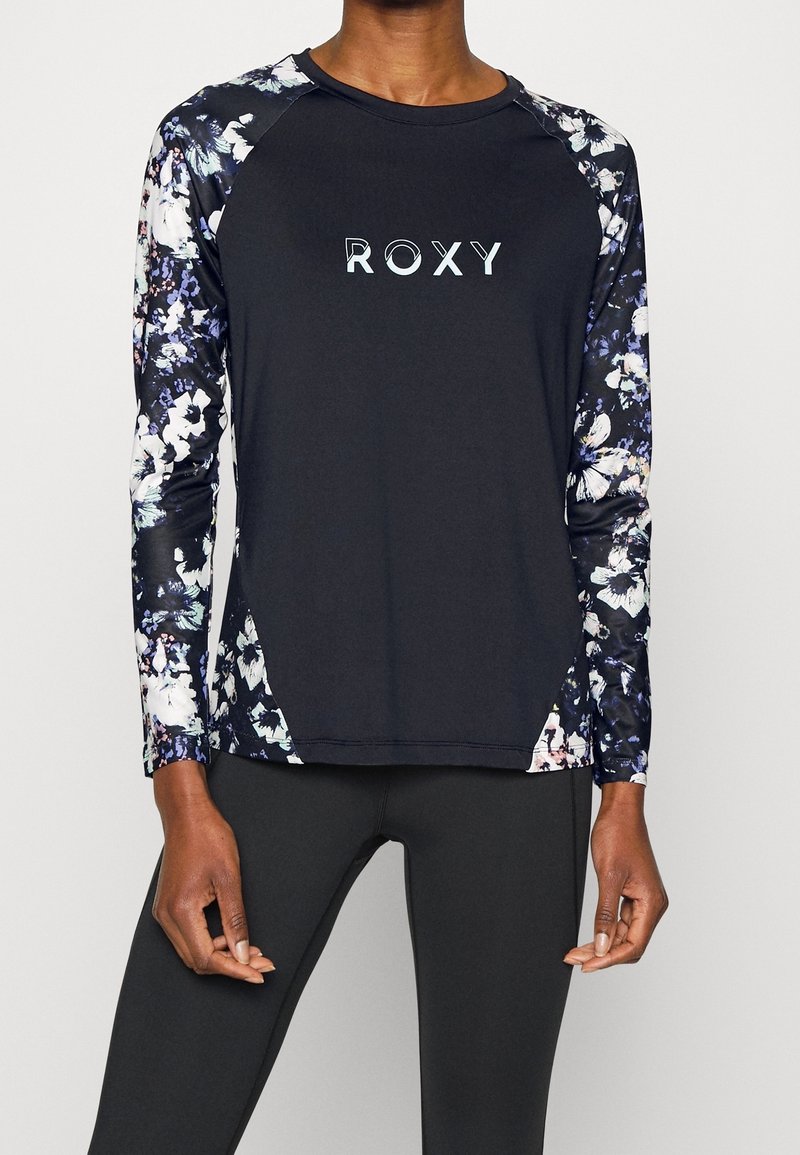 Pitkähihaiseen urheiluyläosaan kuuluu musta body, jossa on kukkakuosiset hihat. Etupuolella on valkoisella tekstillä "ROXY"-logo.