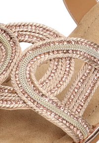 Correa de textil trenzada en oro y beige con acentos metálicos, que incluye una plantilla acolchada en tono marrón y una superficie suave.