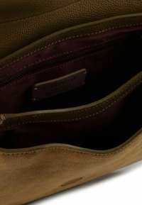 Borsa a mano in pelle verde oliva con esterno liscio, dettagli in suede e texture, fodera in tessuto bordeaux e tasca interna con cerniera.