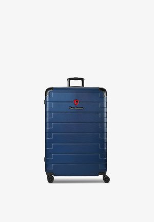 Blauwe harde koffer met vier wielen, een zwart uitschuifbaar handvat en een rood logo vlakbij het bovenste midden.