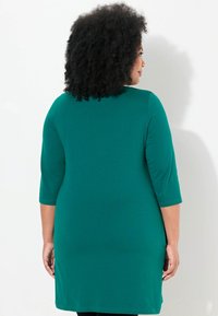 Türkises Kleid in Knielänge mit Dreiviertelärmeln; glatte Textur und runder Ausschnitt. Minimales Design, keine sichtbaren Muster oder Beschläge.