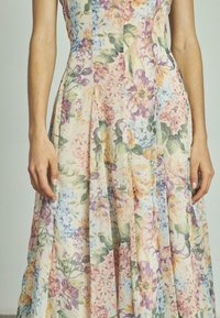 Robe florale en tissu léger avec des couleurs pastel. Comprend des plis et un motif de diverses fleurs dans des tons de rose, violet et bleu.